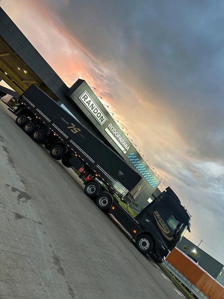 Volvo FH preto da Delamura com rodotrem novo em frente à concessionária Randon Rodoparaná